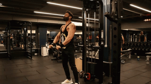 A Man Wearing A Tank Top That Says Los Angeles Is Lifting Weights In A Gym GIF