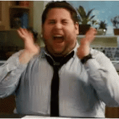 A Man Wearing A Tie And A Blue Shirt Is Making A Funny Face . GIF