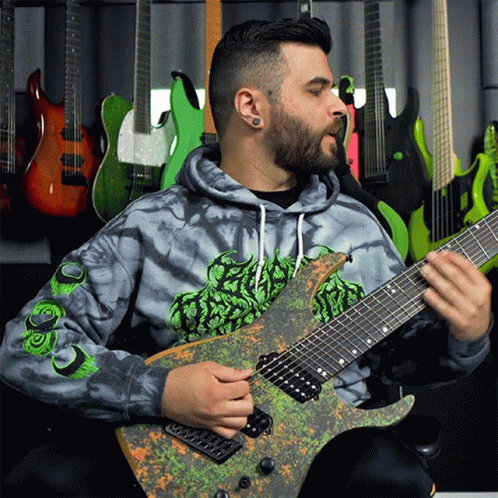 A Man Wearing A Tie Dye Hoodie Playing A Guitar GIF