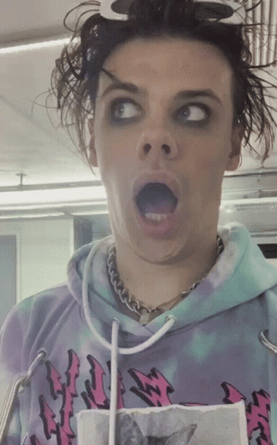 A Man Wearing A Tie Dye Hoodie With A Cat On It Makes A Funny Face GIF
