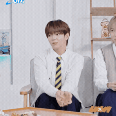 A Man Wearing A Tie Is Sitting In A Chair GIF