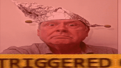A Man Wearing A Tin Foil Hat Is Standing In Front Of A Yellow Sign That Says Triggered GIF