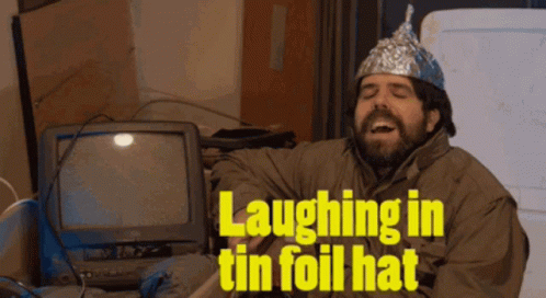 A Man Wearing A Tin Foil Hat Laughs In Front Of A Computer GIF