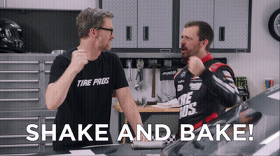 A Man Wearing A Tire Pros Shirt Stands Next To Another Man In A Garage GIF