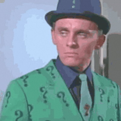 A Man Wearing A Top Hat And A Green Jacket With Question Marks On It . GIF