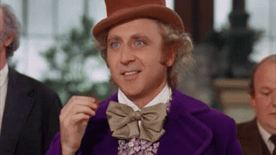 A Man Wearing A Top Hat And A Purple Jacket Is Eating A Chocolate Bar . GIF