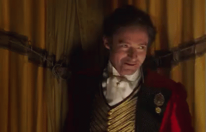 A Man Wearing A Top Hat And A Red Jacket Is Standing In Front Of A Crowd . GIF
