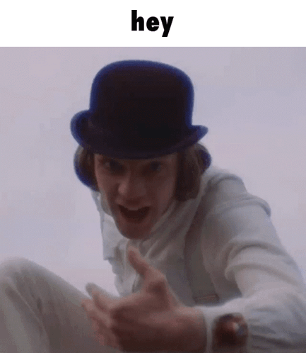 A Man Wearing A Top Hat And A White Shirt Is Making A Funny Face And Saying Hey . GIF