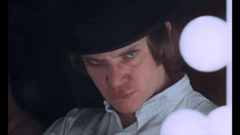 A Man Wearing A Top Hat And A White Shirt Looks At The Camera GIF