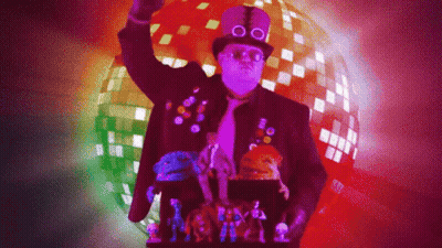 A Man Wearing A Top Hat And Glasses Is Standing In Front Of A Disco Ball GIF