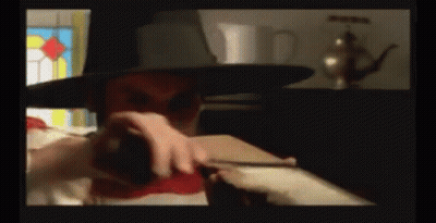 A Man Wearing A Top Hat Is Holding A Red Object GIF