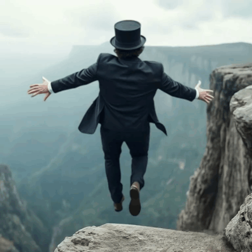 A Man Wearing A Top Hat Is Jumping Over A Cliff GIF