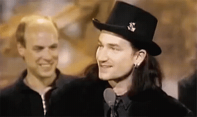 A Man Wearing A Top Hat Is Talking Into A Microphone . GIF
