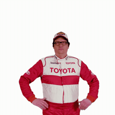 A Man Wearing A Toyota Jacket And A Superman Shirt Holds His Fist Up In The Air GIF