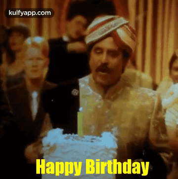 A Man Wearing A Turban Is Blowing Out A Candle On A Birthday Cake And Says Happy Birthday . GIF