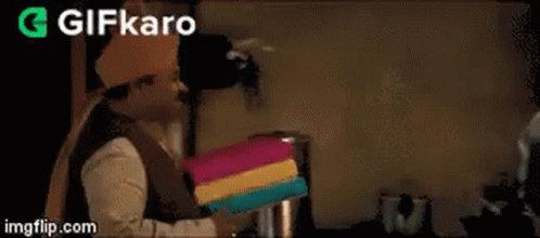 A Man Wearing A Turban Is Holding A Gift Box And Says `` Happy Anniversary '' . GIF
