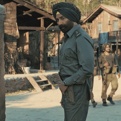 A Man Wearing A Turban Stands In Front Of A Building GIF