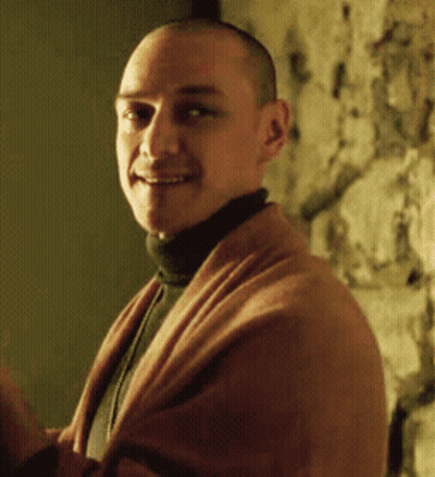 A Man Wearing A Turtleneck And A Brown Sweater Smiles For The Camera GIF