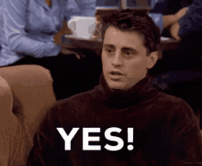 A Man Wearing A Turtleneck Sweater Is Sitting On A Couch And Saying Yes . GIF