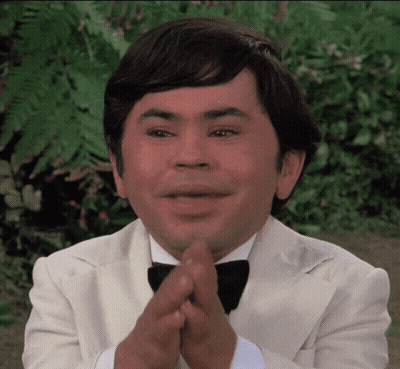 A Man Wearing A Tuxedo And Bow Tie Is Clapping His Hands GIF