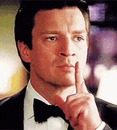 A Man Wearing A Tuxedo And Bow Tie Is Holding His Finger To His Mouth . GIF