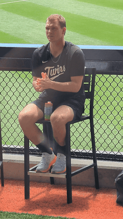 A Man Wearing A Twins Jersey Sits On A Chair GIF