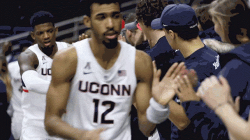 A Man Wearing A Uconn Jersey Is Being High Fived GIF