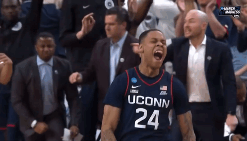 A Man Wearing A Uconn Jersey Is Celebrating GIF