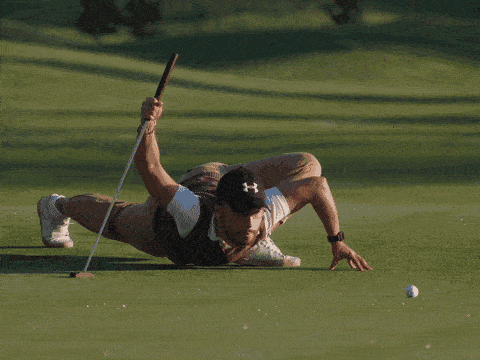 A Man Wearing A Under Armour Hat Is Playing Golf On A Green GIF