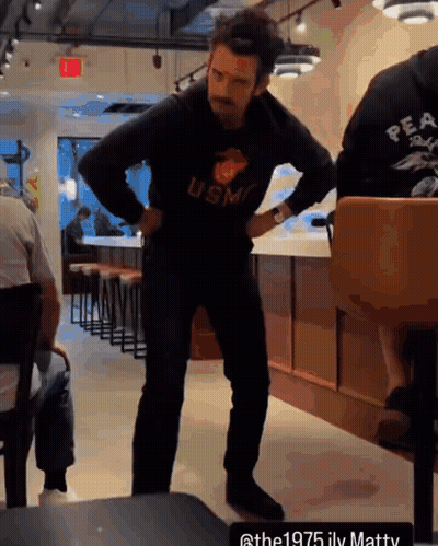 A Man Wearing A Usmc Sweatshirt Stands In A Restaurant GIF
