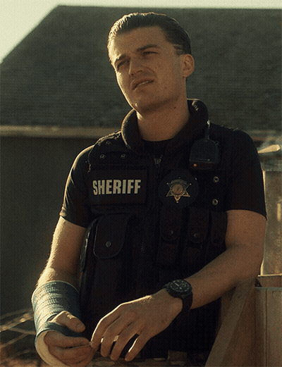 A Man Wearing A Vest That Says Sheriff On The Back GIF