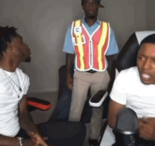 A Man Wearing A Vest With The Letter C On It Talks To Two Other Men GIF