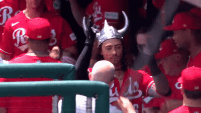 A Man Wearing A Viking Hat Stands In A Crowd Of Baseball Players Wearing Red Jerseys With The Letter R On Them GIF