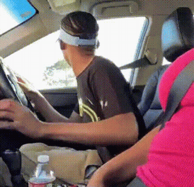 A Man Wearing A Visor Is Driving A Car Next To A Bottle Of Water GIF