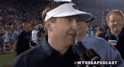 A Man Wearing A Visor Is Talking Into A Microphone . GIF