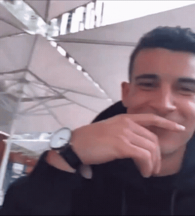 A Man Wearing A Watch Is Laughing And Covering His Mouth GIF