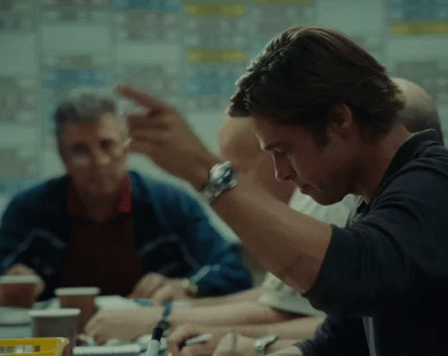 A Man Wearing A Watch Is Sitting At A Table With Other Men GIF