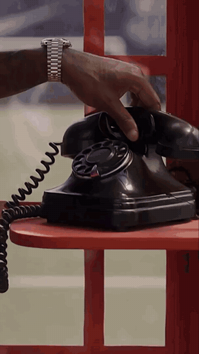 A Man Wearing A Watch Is Talking On A Black Telephone GIF
