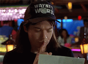 A Man Wearing A Wayne World Hat Holds His Finger To His Mouth GIF