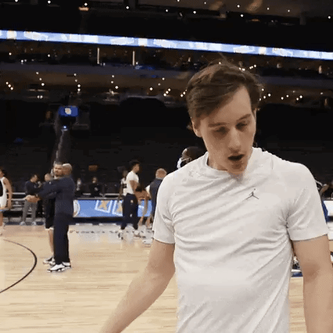 A Man Wearing A White Air Jordan T-Shirt Is Standing On A Basketball Court GIF