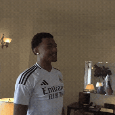a man wearing a white emirates fly better shirt is making a heart shape with his hands