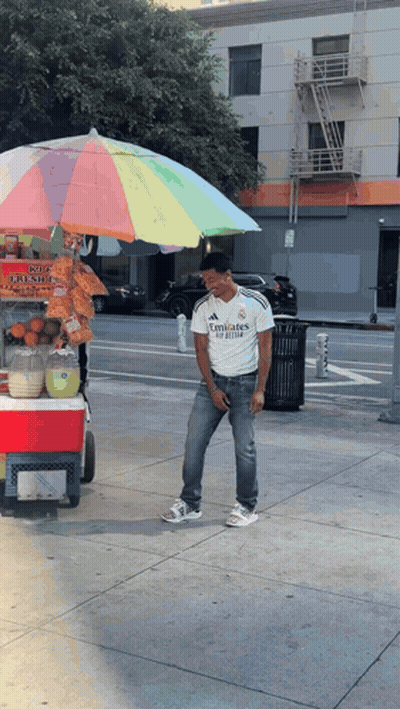A Man Wearing A White Emirates Shirt Stands In Front Of A Cart GIF