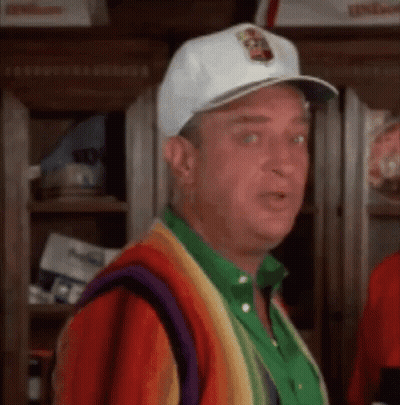 A Man Wearing A White Hat And A Colorful Sweater Is Standing In A Room . GIF