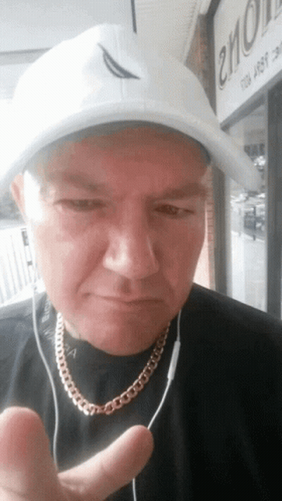 A Man Wearing A White Hat And A Gold Chain Is Giving The Thumbs Up Sign GIF