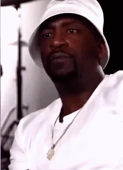 A Man Wearing A White Hat And A Necklace Looks At The Camera GIF