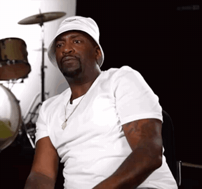 A Man Wearing A White Hat And A White Shirt Sits In Front Of A Drum Set GIF