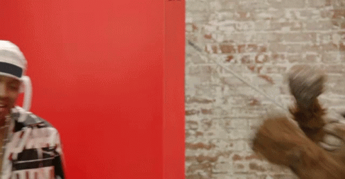 A Man Wearing A White Headband Is Standing In Front Of A Brick Wall GIF
