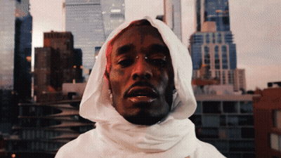 A Man Wearing A White Hooded Sweatshirt With A City Skyline In The Background GIF