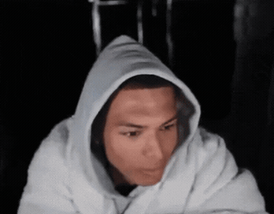 A Man Wearing A White Hoodie Looks At The Camera GIF