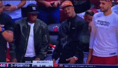 A Man Wearing A White Hot Playoffs Shirt Is Standing In The Stands During A Basketball Game GIF